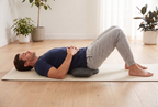 Man lying on a floor mat with the CoreRest under the small of his back